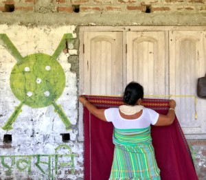 An Aagor staff member measures the fabric brought in by a home-based weaver, at a village collection meeting.